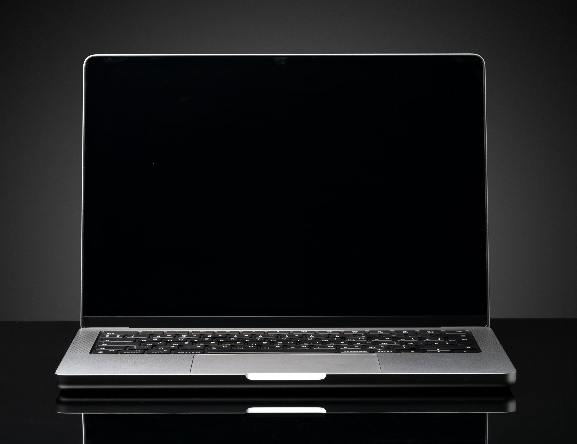 A MacBook on a dark desk running MiniPrompter. A warm band of light runs around the
              edge of the screen, and a script scrolls in a window that reaches the very top of the
              display and passes behind the notch, with a thin red reading line across it.